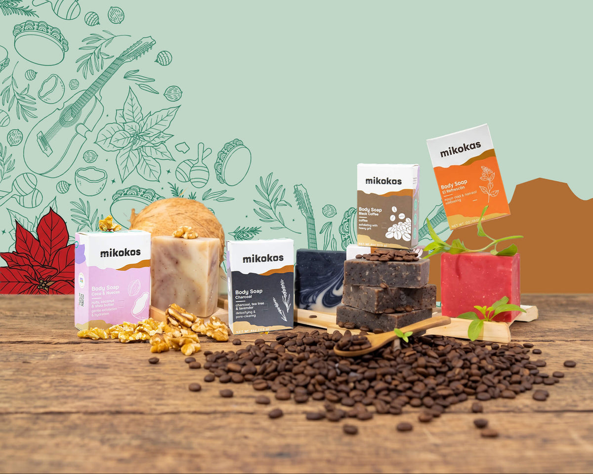 Jabones corporales Mikokos de Coco & Nueces, Charcoal, Black Coffee y El Refrescón sobre madera con granos de café y nueces, con ilustraciones navideñas de cuatro, maracas y flor de pascua