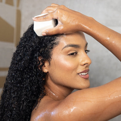 Mujer lavando su cabello rizado con el shampoo en barra Koko de Mikokos