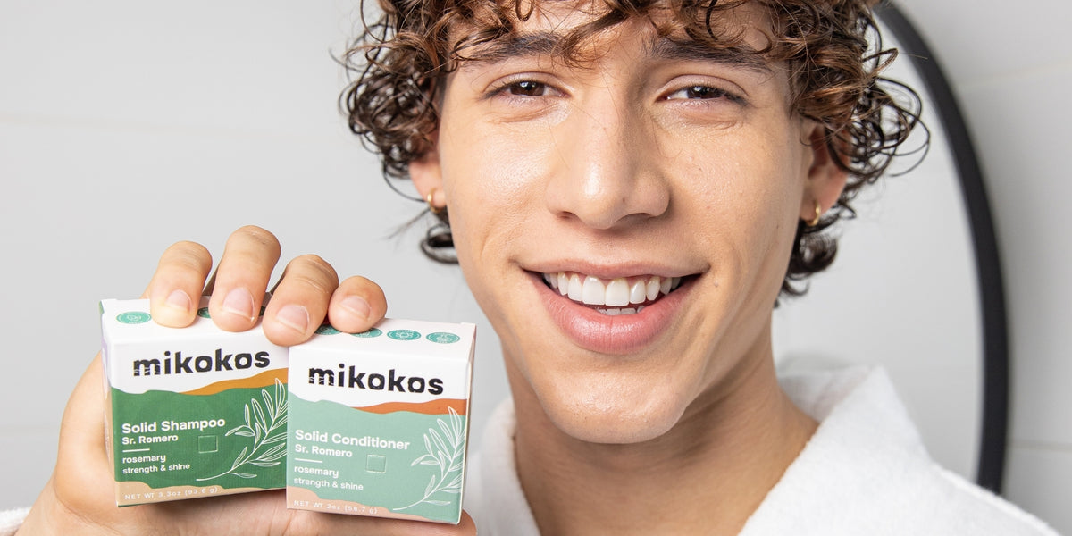 Joven sonriendo con el shampoo y el acondicionador Sr. Romero