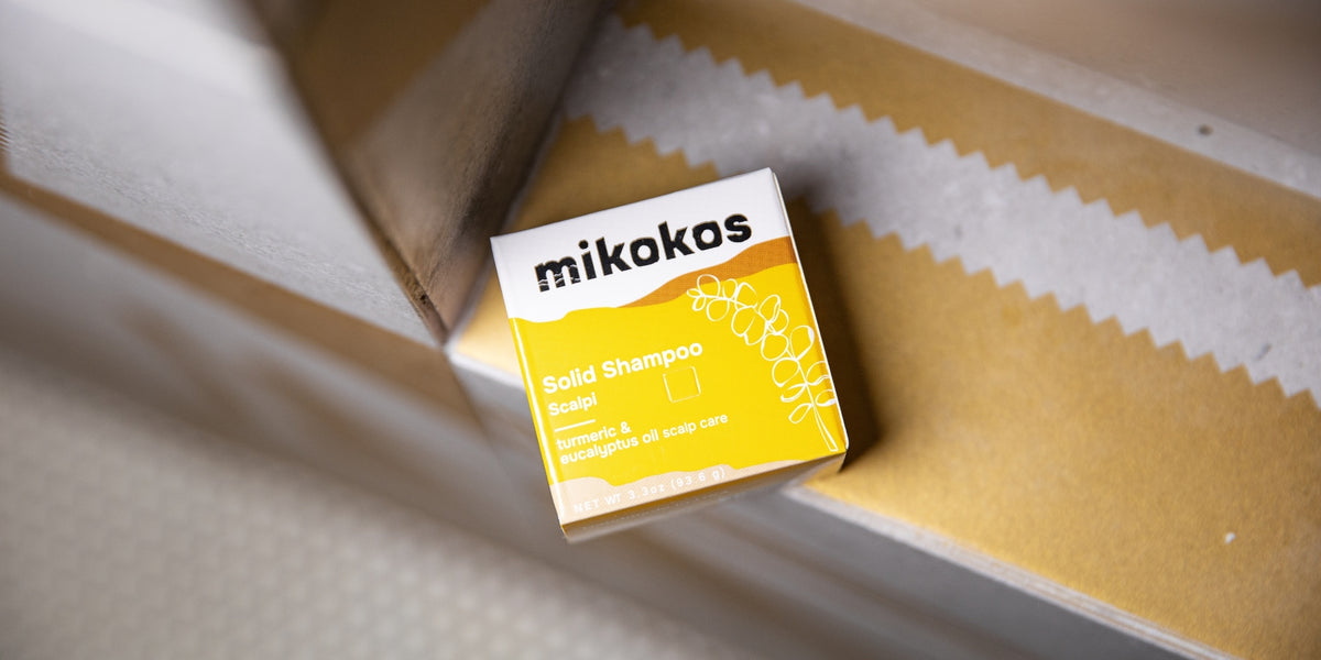 Caja de Scalpi Shampoo en Barra de Mikokos sobre papel de embalaje, con cúrcuma y eucalipto